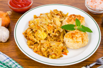 Stewed cabbage, meat cutlets, spices, salt on wooden table.