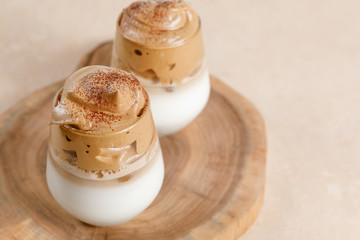 Dalgona coffee - the Korean coffee drink on light beige background.  Instant coffee or espresso powder whipped with sugar and hot water