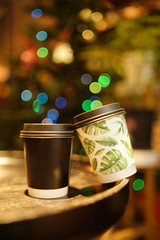 Cardboard coffee cups standing on coffee table with bokeh around