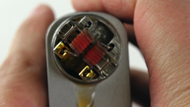 Vaping atomizer with clapton coil is working on a white background.