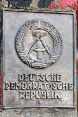 Old original German Democratic Republic GDR border frontier post with metal coat of arms, the National emblem of East Germany.