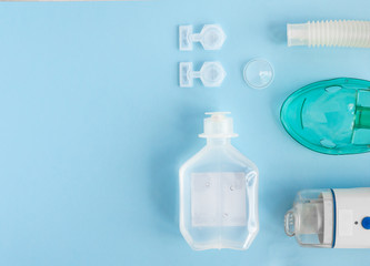 Set of compact ultrasonic inhaler, nebulizer and medicines on blue background. Flat lay, top view