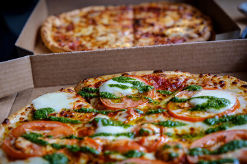 Closeup of tasty takeaway italian pizza inside its deliver service paper box.