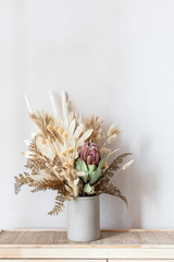 Minimalistic composition of dried flowers in cylindrical ceramic vase as home decoration. Vertical...