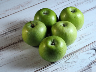 Five juicy green apples on wooden background