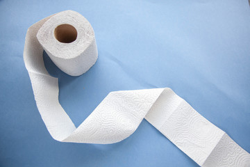Unwinding toilet paper on a blue background. toilet paper deficiency coronovirus
