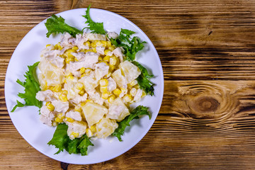 Festive salad with chicken breast, canned pineapple, cheese, sweet corn and mayonnaise on wooden table. Top view