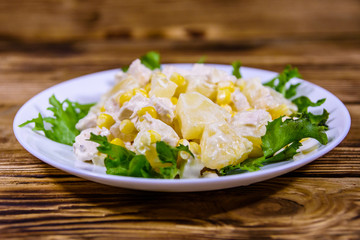 Festive salad with chicken breast, canned pineapple, cheese, sweet corn and mayonnaise on wooden table