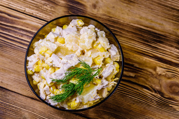 Festive salad with chicken breast, canned pineapple, cheese, sweet corn and mayonnaise on wooden table. Top view