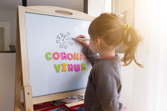 Une fillette dessine le symbole du corona virus sur un tableau blanc