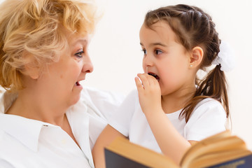 Grandmother reading a tale to her baby granddaughter. Family Reading Leisure. Quality Time. Happy Family having fun playing at home.