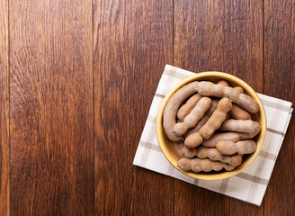 tamarind  in a wooden bowl on a wooden table, top view.