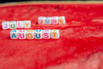 The inscriptions of the june, july and august is made of cubes with letters lying on a watermelon