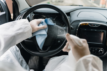 Cleansing car interior and spraying with disinfection liquid. Hands in rubber protective glove disinfecting 
steering wheel for protection from virus disease. Pandemic сoronavirus protection сoncept.