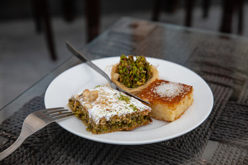tasty arabic sweet dessert with pistachios on white plate in typical local cafe in Doha City