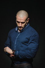 A stylish, bald young man stands on a dark background in the category. Business, Finance
