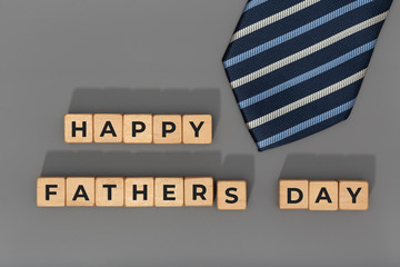 Happy Fathers Day blocks with tie on gray background. Celebration event background. Copy space