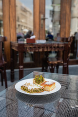 tasty arabic sweet dessert with pistachios on white plate in typical local cafe in Doha City