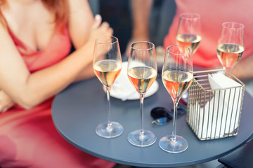 Close-up detail table with many filled glasses of white champagne prosecco at party celebration event outdoors. People having fun enjoy drink alcohol toasting cheers at cafe restaurant on summer day