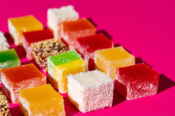 Turkish delight square pieces on a bright pink background close up