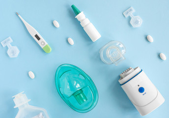 Flat lay with set of medication, thermometer, pills, inhaler, spray, face mask Treatment of flu and colds, pneumonia. Top view of the medicine on blue background, copy space