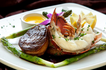 Bacon Wrapped Filet Mignon and Lobster Tail with Asparagus, Melted Butter, and Lemon Wedge - Gourmet Dinner Plate