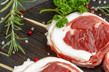 fresh meat with ingredients for cooking on dark background, close up