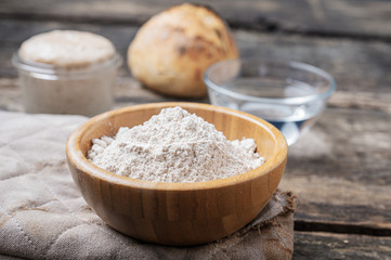 Fototapeta na wymiar Closeup view of organic whole spelt flour in wooden cup