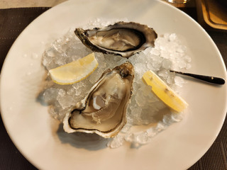 Fresh Oysters with lime on a large plate with ice.