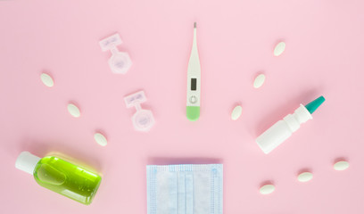 Flat lay with set of medicine, thermometer, pills, medical mask, sanitizer, spray. treatment of flu and colds. Top view, medication on pink background