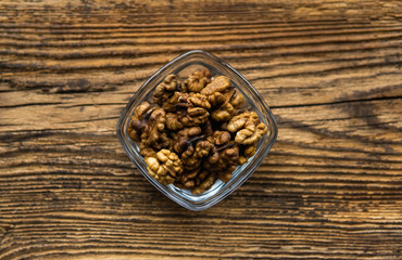 Obraz na płótnie Canvas Walnut in a small plate on a vintage wooden table as a background. Walnuts is a healthy vegetarian protein nutritious food. Natural nuts snacks.