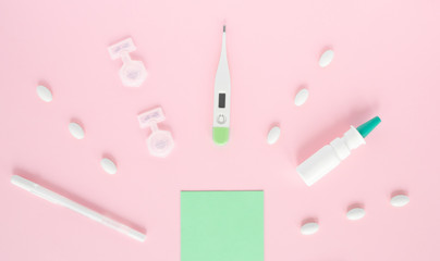 Flat lay with set of medication, thermometer, pills, piece of paper, sanitizer, spray,  pen. Treatment of flu and colds. Top view of the medicine on pink background