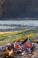 Smoldering ashes of a bonfire. Incandescent orange and red embers texture. At the river