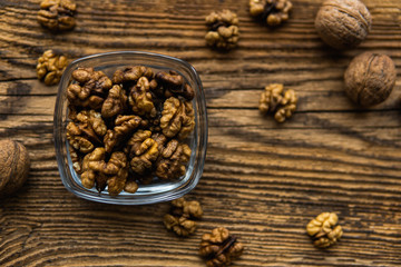 Walnut in a smale plate with scattered shelled nuts and whole nut which standing on a wooden vintage table. Walnuts is a healthy vegetarian protein nutritious food. Walnut on rustic old wood.
