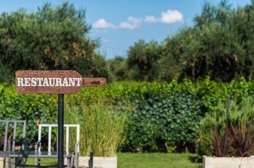 Arrow sign saying restaurant against the background of green trees. Concept of restaurant and hospitality business.