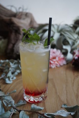 Red and yellow cocktail with a straw served in a tall cocktail glass