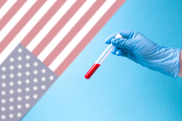 hand in a blue disposable rubber glove holds a test tube with blood, blue background, white background for text, copy space