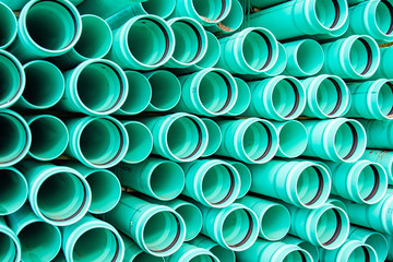 Large plastic pipes are stacked creating an abstract pattern while waiting to be installed under...