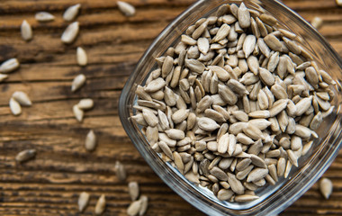 Sunflower seeds in a small plate and scattered seed on the wooden vintage table. Healthy vegetarian protein nutritious food. Sunflower seed on rustic old wood.