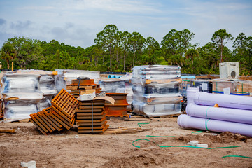 Pallets and piles of construction material are sitting at a job site, waiting to be utilized.