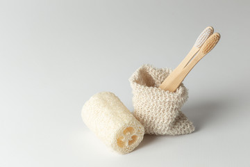two toothbrushes made of natural wood and natural loofah in an ecological bag. zero waste. on a gray background - obrazy, fototapety, plakaty