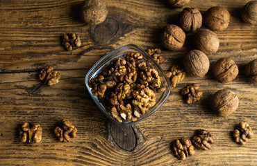 Walnut in a smale plate with scattered shelled nuts and whole nut which standing on a wooden vintage table. Walnuts is a healthy vegetarian protein nutritious food. Walnut on rustic old wood.