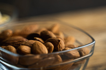 Almonds in a small plate on a vintage wooden table as a background with a copy space. Almond is a healthy vegetarian protein nutritious food. Natural nuts snacks.