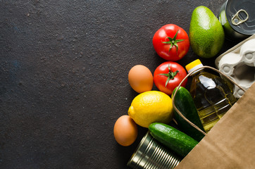 Paper bag with various groceries on dark concrete background. Food delivery concept. Food donations.