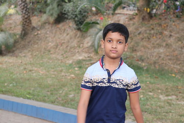 School boy enjoing at park in his childhood; Portrait of a beautiful boy closeup. Cute schoolboy in the park.