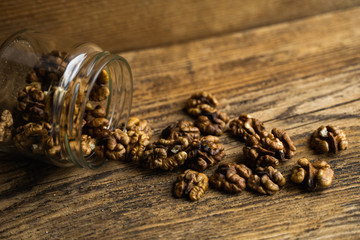 Walnut scattered on the wooden vintage table from a jar. Walnut is a healthy vegetarian protein nutritious food. Walnut kernels and whole walnuts on rustic old wood.
