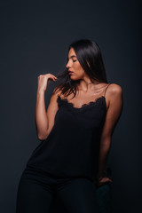 Fototapeta premium Beautiful sexy woman with straight black hair looking aside and being isolated on a dark background