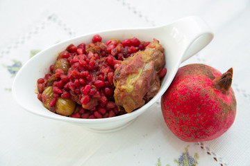 The Living Pomegranate is on a white tablecloth . Roasted pomegranet seeds . Baked pomegranate seeds and chicken .