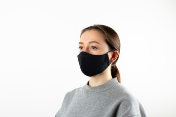 Portrait of young woman wearing black face mask isolated on gray background. Dust protection...