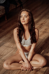 Photo of a beautiful female model posing while relaxing on a wooden floor in a luxury apartment wearing sporty underwear